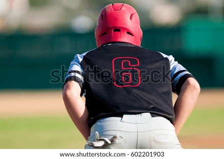 Teenage american baseball boy on base ready to steel.