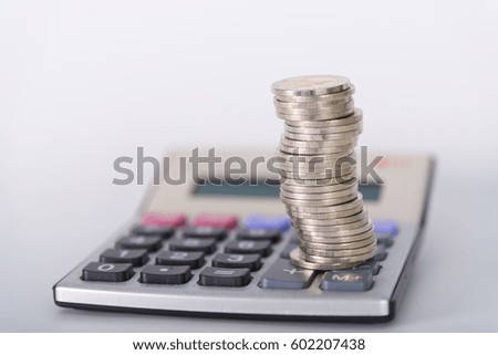 Savings, increasing columns of coins, piles of coins arranged as a graph and calculator on white background, business idea, shallow focus.