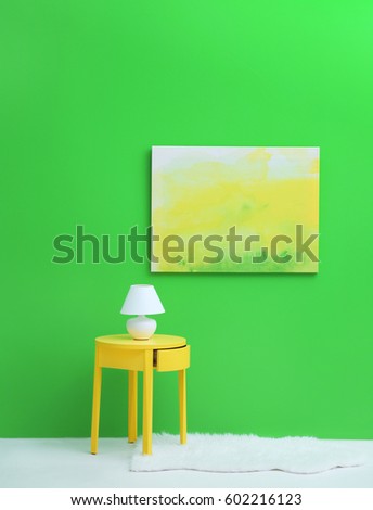 Lamp on little yellow table near green wall
