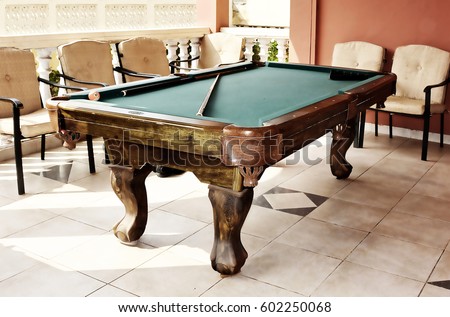 Beautiful photo of stylish pool table with a cue and billiard balls on a nice patio. Snooker. Old photo. Stunning vintage. Glow background.  