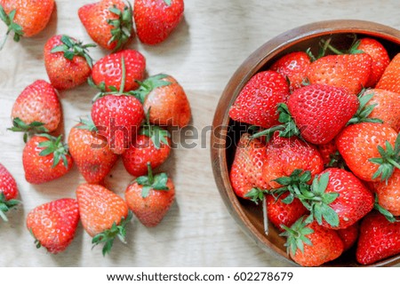 Fresh strawberry in wooden bowl on table.