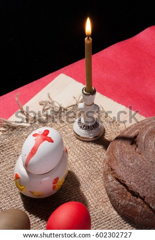 Painted egg on the table with bread and a burning candle