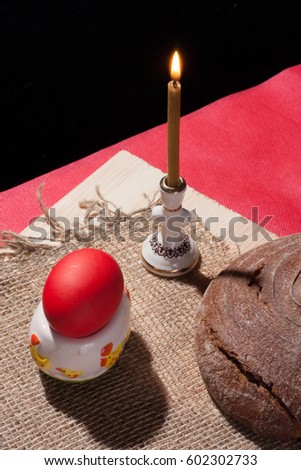 Painted egg on the table with bread and a burning candle