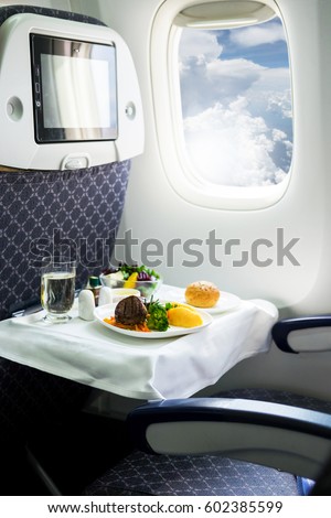 Commercial passengers airplane interior of seat chairs, window and tray with food