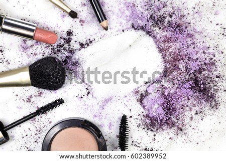 Makeup brushes, pencil, lipstick and other objects, forming a frame on a light background, with crushed powder and copy space. A horizontal template for a makeup artist's business card or flyer design