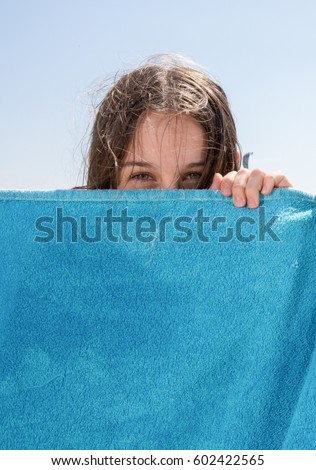 woman hides on the sea behind her blue beach towel