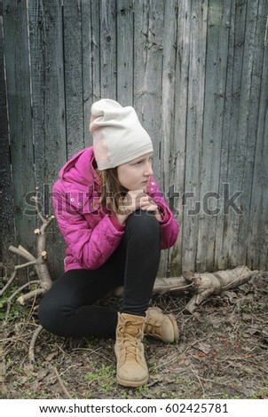 Teen girl sitting near the old fence