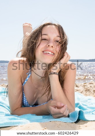 Pretty Young beautiful young woman is lying on her towel on the sand of the beach
