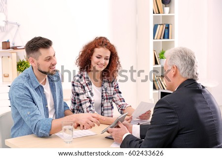 Young couple signing contract at insurance agency office