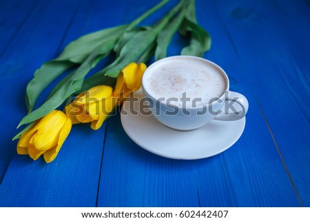 Coffee mug with yellow tulip flowers and notes good morning on blue rustic table from above, breakfast on Mother's day or Women's day .Spring  flowers bouquet