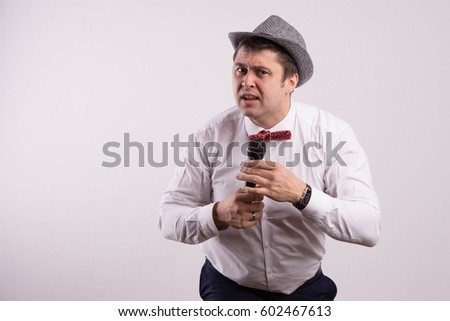 Man in shirt attractive on light background in hat with microphone leading, toastmaster cheerful cool
