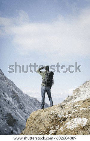 A man hiking in the mountains standing on an outcrop looking at the view