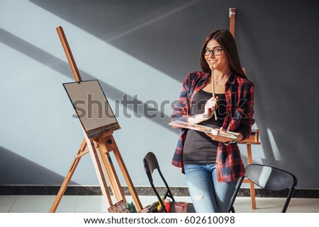 Young woman artist painting a picture in studio.