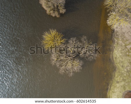 Top Aerial view of spring flood. Drone top view of trees in frozen river. 