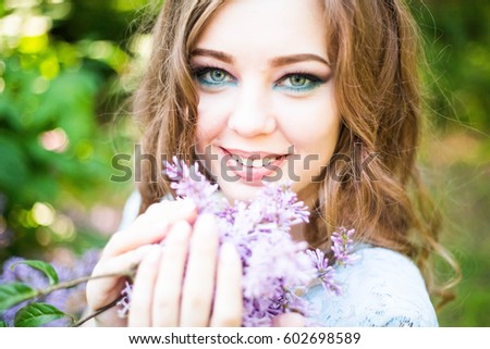 Portrait of a smiling girl with a lilac in hands