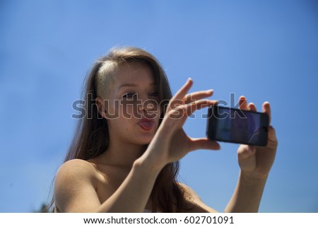 Outdoor lifestyle portrait of pretty young woman having fun in the city in Europe taking pictures with mobile phone