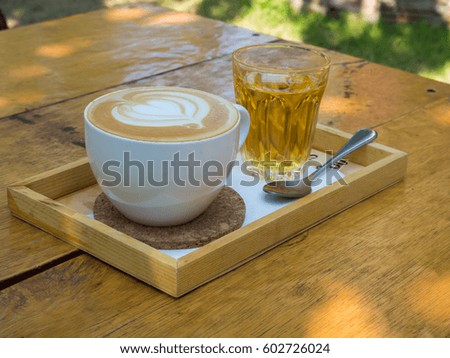 a cup of latte art coffee (heart picture) ,tea and spoon on wooden plate