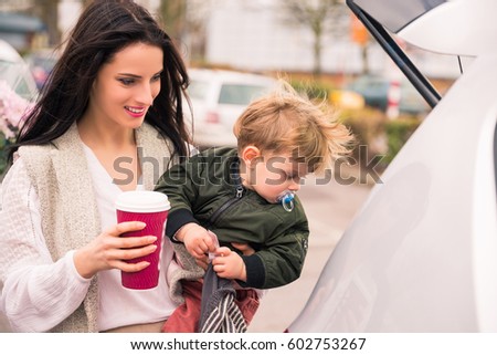 Woman with little son near car after shopping in grocery shopping
