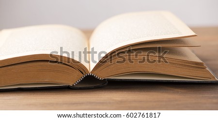 Close-up of an open book on brown wooden table.