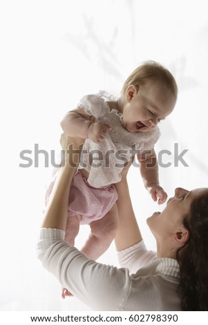 Mother holding up laughing baby girl