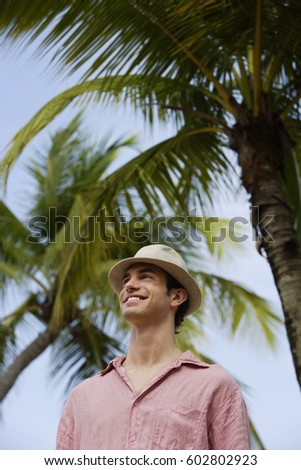man standing under palm tree