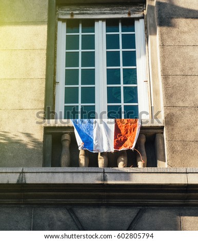 French tricolor flag hanging from window on a Paris building - French patriotism concept 
