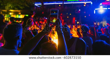 Video recording of the concert on the smartphone phone of the Beach party. Blue conceptual background of the youth party.