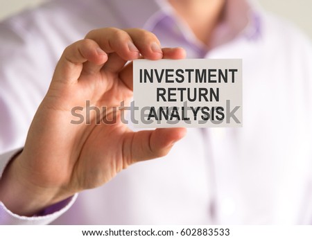 Closeup on businessman holding a card with INVESTMENT RETURN ANALYSIS message, business concept image with soft focus background