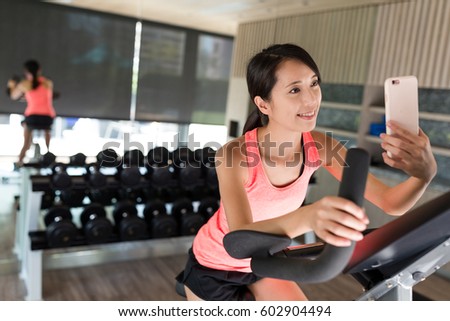Woman biking at gym and taking selfie