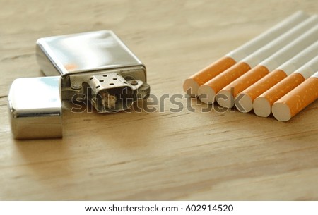 silver lighter and cigarette on wooden board