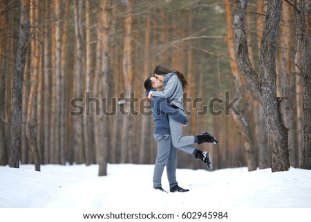 Winter snow couple love story in the forest. Happy romantic smiling lovers hugging in the snowy winter outdoors.People and love concept. Young couple of families