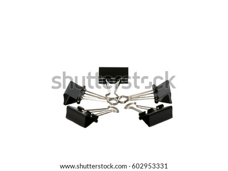 A lot of black metal clamps isolated on white background. Stationery and goods. Selective focus. Horizontal arrangement.