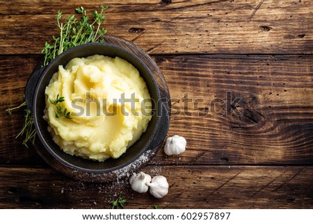 Mashed potatoes, boiled puree in cast iron pot on dark wooden rustic background, top view Royalty-Free Stock Photo #602957897