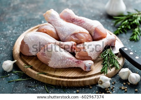 Raw uncooked chicken legs, drumsticks on wooden board, meat with ingredients for cooking Royalty-Free Stock Photo #602967374