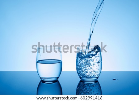 Creative splashing water in the glass on blue background.  