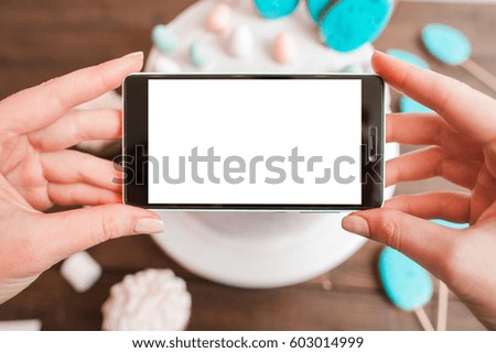Food photography of white cake on wooden table background. Smartphone mockup with blank screen. Small business, culinary blog, social network, delivery of sweets concept