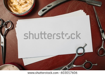 Blank card with scissors and razor flat lay. Top view on red table with shaving and cutting instruments, free space for text. Beauty, barbershop, manhood concept