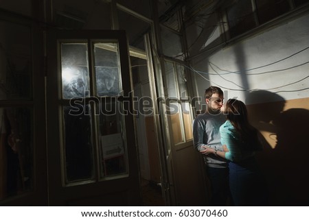 young man and woman standing in a dark corridor. Large windows in the old interior. Forbidden love
