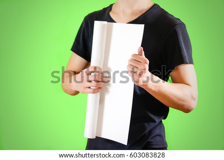 Guy holds in his hands twisted up in paper. Opens the package of paper. Shows a blank sheet rolled into a tube. Man showing blank white flyer brochure booklet. Man show clear offset paper.