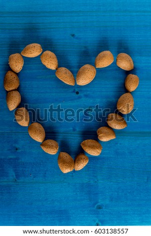 Healthy organic almonds, heart shaped on blue background