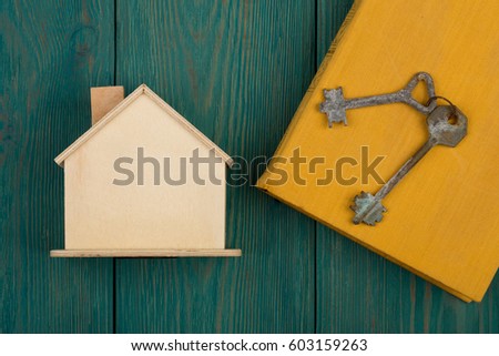 privacy concept - little blank house, book and key on blue wooden desk