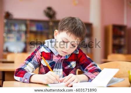 Cheerful, cute sitting at the desk in the school room