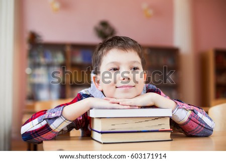 Cheerful, cute, boy, schoolboy sitting at the desk in the school room