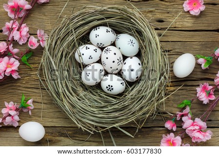 Top view easter background. Happy easter eggs in nest with beautiful pink flowers. Texture rustic old wooden with decorations and copy space. 