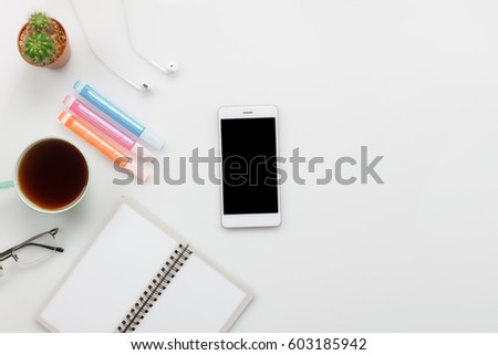 Top view accessories office desk concept. mobile phone, coffee, notepaper, pencil, earphones on white office desk.