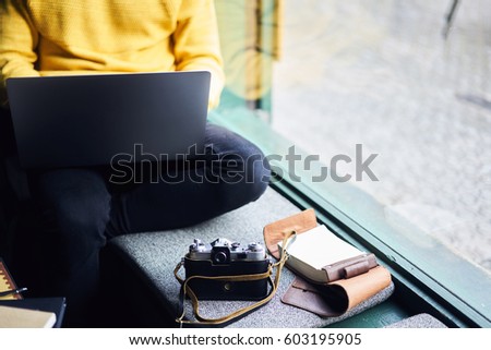 Cropped image of male freelancer preparing project using modern laptop computer connected to free wireless internet in coffee shop editing photos made by vintage camera for fashion online issue