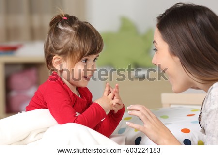 Mother and toddler wearing red shirt playing together on a bed in the bedroom at home Royalty-Free Stock Photo #603224183