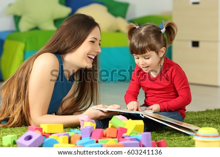 Mother and toddler playing together with a book lying on the floor in the bedroom at home with a colorful background Royalty-Free Stock Photo #603241136