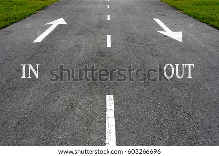 Opposite arrow on the asphalt road with text in and out.