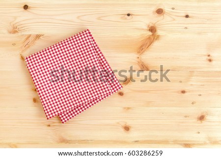 Checkered red and white napkin or folded tablecloth on wooden background with copy space